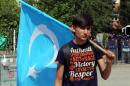 An Uighur boy carries a flag of East Turkestan, the term separatist Uighurs and Turks use to refer to the Uighurs' homeland in China's Xinjiang region,after the riot police used pepper spray to push back a group of Uighur protesters who try to break through a barricade outside the Chinese Embassy in Ankara, Turkey, Thursday, June 9. 2015. Thailand sent back to China more than 100 ethnic Uighur refugees on Thursday, drawing harsh criticism from the U.N. refugee agency and human rights groups over concerns that they face persecution by the Chinese government. Protesters in Turkey, which accepted an earlier batch of Uighur refugees from Thailand, ransacked the Thai Consulate in Istanbul overnight.(AP Photo/Burhan Ozbilici)
