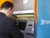 A man withdraws money from an ATM at a branch of Bank of Cyprus in Bucharest