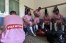 In this photo taken Sunday, Oct. 7, 2012, Voukefalas players, a small amateur soccer club, get ready in a changing room before a local championship match in the city of Larissa, central Greece. A cash-strapped Greek soccer team has found a new way to pay the bills, with help from the world's oldest profession. Players are wearing bright pink practice jerseys emblazoned with the logos of the Villa Erotica and Soula's House of History, a pair of pastel-colored bordellos recruited to sponsor the team after drastic government spending cuts left the country's sports organizations facing ruin. One team took on a deal with a local funeral home and others have wooed kebab shops, a jam factory, and producers of Greece's trademark feta cheese. But the small amateur Voukefalas club which includes students, a bartender, waiters and pizza delivery drivers is getting the most attention for its flamboyant sponsors. (AP Photo/Nikolas Giakoumidis)