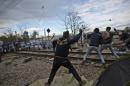 Migrants hurl stones at Macedonian policemen during clashes at the Greek-Macedonian border, near the northern Greek village of Idomeni, on Saturday, Nov. 28, 2015. Tension has flared on the Greek side of the Greece-Macedonia border when a migrant who was stopped from crossing into Macedonia, suffered severe burns when he climbed on top of a stationary train carriage and touched a overhead power cable.(AP Photo/Muhammed Muheisen)