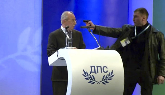 Image grab from video shows a man identified as Oktai Enimehmedov, 25, as he points a weapon at Ahmed Dogan, left, leader of the Movement for
 Rights and Freedoms, during his speech at his party's congress in Sofia, on Saturday Jan. 19, 2013. Dogan struck the man before other delegates wrestled the assailant to the ground, and no shots were fired. Police took the man away.(AP Photo/ BTVnews)