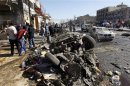 Residents gather at the site of a car bomb attack in the AL-Mashtal district in Baghdad