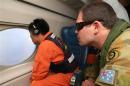 Crew member Koji Kubota and John Pumpa of the RAAF look out an observation window aboard the Japan Coast Guard Gulfstream V aircraft as it flies over the southern Indian Ocean looking for debris from missing Malaysian Airlines flight MH370