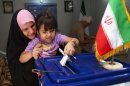 A little girl helps her mother with casting a ballot at a polling center during the presidential election in Basra, 340 miles (550 kilometers) southeast of Baghdad, Iraq, Friday, June 14, 2013. Iranian voters appeared to heed calls to cast ballots Friday in a presidential election that has suddenly become a showdown across Iran's political divide: Hard-liners looking to cement their control and re-energized reformists backing the lone moderate left in the race. (AP Photo/ Nabil al-Jurani)