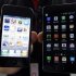 An employee of South Korean mobile carrier KT holds an Apple Inc's iPhone 4 smartphone and a Samsung Electronics' Galaxy S II smartphone as he poses for photographs at a registration desk at KT's headquarters in Seoul