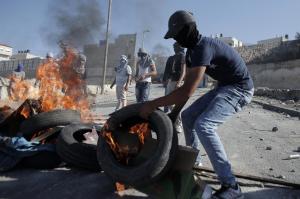 A Palestinian protester burns a tire during clashes …