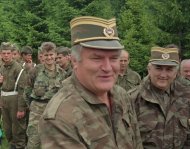 Bosnian Serb military commander General Ratko Mladic, center, smiles as he visits troops to mark both the fourth anniversary of the founding of his Bosnian Serb army and St. Vitus' Day, the anniversary of the Serb defeat by the Turks at Kosovo in 1389, near the village of  Han Pijesak, some 40 miles east of Sarajevo, Friday June 28, 1996. Mladic, indicted for war crimes by the United Nations in The Hague, Netherlands for atrocities, has been sacked, according to a statement released early Saturday  Nov. 9, 1996, by the Bosnian Serb president Biljana Plavsic. (AP Photo/STR)