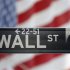 A sign for Wall Street is seen with a giant American flag in the background across from the New York Stock Exchange