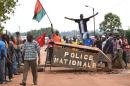 A man waves the Burkina Faso flag (L) as people protest in the city of Hounde, capital of Tuy Province, in east central Burkina Faso, on September 19, 2015