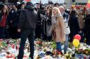 A woman shouts at a man walking amongst floral tributes in area outside the Stock Exchange in Brussels, on March 27, 2016