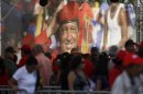 A large image of Venezuela's late President Hugo Chavez is on display where mourners line up to view his body lying in state at the military academy in Caracas, Thursday, March 7, 2013. While Venezuela remains deeply divided over the country's future, the multitudes weeping and crossing themselves as they reached the president's coffin early Thursday were united in grief and admiration for a man many considered a father figure. (AP Photo/Ariana Cubillos)