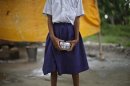 A school girl holds a container to receive free mid-day meal, distributed by a government-run primary school, at Brahimpur village in Chapra