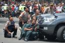 Indonesian police take position behind a vehicle as they pursue suspects after a series of blasts hit the Indonesia capital Jakarta