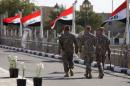 Iraqi flags fly in the wind as US soldiers walk at Camp Victory on December 1, 2011