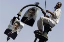 A member of the Muslim Brotherhood and supporter of ousted Egyptian President Mohamed Mursi places posters of Mursi on a lamp post during a protest in front of the courthouse and the Attorney General's office in Cairo