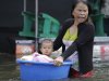 A woman pushes a baby on a plastic container as they wade through floods in Rangsit district on the outskirts of Bangkok, Thailand on Friday Oct. 21, 2011. Thailand's prime minister Yingluck Shinawatra urged Bangkok's residents to get ready to move their belongings to higher ground Friday as the country's worst floods in half a century began seeping into the capital's outer districts. (AP Photo/Aaron Favila)