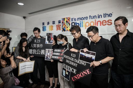 Survivors and relatives of eight Hong Kong tourists who were killed exactly two years ago in a 2010 Philippine bus hostage fiasco in Manila gather outside the Philippines consulate in Hong Kong to demand an apology