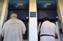 Men withdraw money from an ATM in Athens