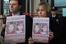 Gerry (L) and Kate McCann pose with boards showing their missing daughter Madeleine reading "don't give me up" as they leave the Tribunal Civil de Lisboa in Lisbon on February 10, 2010