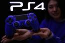 Staff at the PlayStation 4 launch event poses with PlayStation 4's game controller before its domestic launch event at the Sony Showroom in Tokyo