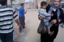 This image taken from video obtained from Shaam News Network, which has been authenticated based on its contents and other AP reporting, shows a woman carrying a child running away from the scene of shelling in Qouriyeh, Syria, Friday, Nov. 9, 2012. (AP Photo/Shaam News Network via AP video)