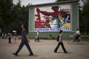 People walk past a roadside propaganda billboard promoting the "military first" policy and a boost to build the country's economy in Pyongyang, North Korea, Sunday, June 16, 2013. North Korea's top governing body on Sunday proposed high-level nuclear and security talks with the United States in an appeal sent just days after calling off talks with rival South Korea. (AP Photo/Alexander Yuan)