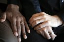 In this photo taken on Monday, Oct. 22, 2012, the hands of Ludovic-Mohamed Zahed, right, who married his live-in partner Qiyaammudeen Jantjies, left, in South Africa, where gay marriage is recognized, during an interview with the Associated Press in Sevran, outside Paris. A plan to legalize same-sex marriage and allow gay couples to adopt was a liberal cornerstone of French President Francois Hollande's election manifesto earlier this year. It looked like a shoo-in, supported by a majority of the French, and an easy way to break with his conservative predecessor. But that was then, Now, as the Socialist government prepares to unveil its draft "marriage for everyone" law Wednesday, polls show wavering support for the idea and for the president amid increasingly vocal opposition in this traditionally Catholic country. Ludovic-Mohamed Zahed, who married his live-in partner Qiyaammudeen Jantjies in South Africa, where gay marriage is recognized, is already seeking instruction from his local town council to get his marriage recognized in France as soon as he can. (AP Photo/Christophe Ena)