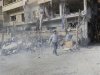 Man carrying a shovel, walks near buildings damaged after what activists said was a Syrian Air Force fighter jet operated by those loyal to Syria's President Bashar al-Assad, fired missiles in Daria