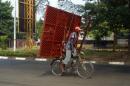 A cyclist carries a metal gate on the back of his bicycle in Bujumbura, Burundi, Sunday July 19, 2015. As Burundians are getting ready to go to the poll Tuesday July 21, three candidates, including two former presidents, announced their withdrawal from Burundi's upcoming presidential race, predicting the contest in this restive African nation will not be free and fair. (AP Photo/Jerome Delay)