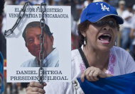 CORRECTS TRANSLATION OF SIGN - A woman shouting holds a picture of Nicaragua's President Daniel Ortega that reads in Spanish "The biggest thief and traitor of Nicaragua, Daniel Ortega, illegal president" at a protest against a canal project outside the National Assembly in Managua, Nicaragua, Thursday, June 13, 2013. A multi-billion dollar proposal to plow a massive rival to the Panama Canal across the middle of Nicaragua was approved by the National Assembly Thursday, capping a lightning-fast approval process that has provoked deep skepticism among shipping experts and concern among environmentalists. (AP Photo/Esteban Felix)
