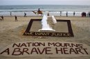 People walk near a sand sculpture with the words "We Want Justice" created by Indian sand artist Sudarshan Patnaik, in solidarity with a gang rape victim who was assaulted in New Delhi, on a beach in the eastern Indian state of Odisha