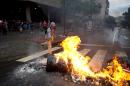 An opposition demonstrator sets a road block on fire in Caracas, Venezuela, Thursday, Feb. 12, 2015. Venezuelans staged dueling marches to mark the anniversary of last year's bloody protest movement that resulted in more than 40 people being killed, including both government supporters and opponents. Dozens of protesters remain jailed, while the social issues they railed against last year- a faltering economy, widespread shortages and pervasive violent crime - have only gotten worse. (AP Photo/Fernando Llano)