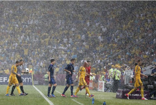 Referee Bjorn Kuipers of Netherlands and soccer players of France and Ukraine teams leave the pitch due to heavy rain during their Group D Euro 2012 soccer match in Donetsk