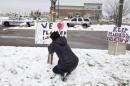 Bethany Winder, a nurse who lives in Colorado Springs, Colo., plants a sign in support of Planned Parenthood just south of its clinic as police investigators gather evidence near the scene of Friday's shooting at the clinic Sunday, Nov. 29, 2015, in northwest Colorado Springs. (AP Photo/David Zalubowski)
