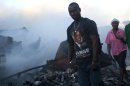 People walk by the remains of a market burned in an overnight fire in the Haitian capital's Market District in Port-au-Prince, Haiti, Saturday, Dec. 29, 2012. The market is one of several that have burned over the past year. (AP Photo/Dieu Nalio Chery)