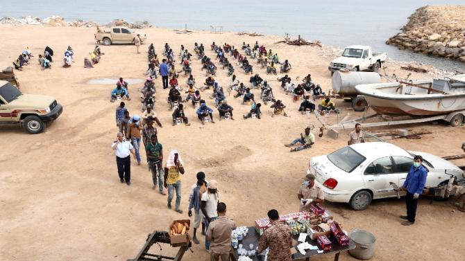Migrants arrested earlier in the week receive food distribution in Tajura, a coastal suburb of the Libyan capital Tripoli on October 10, 2015