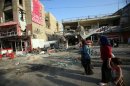 Iraqis walk past a damaged restaurant in the Karrada district of Baghdad on September 4, 2013