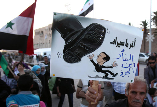 A Syrian man living in Libya holds an anti-Syrian President Bashar al-Assad caricature during a protest