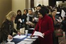 Job seekers adjust their paperwork as they wait in line to attend a job fair in New York