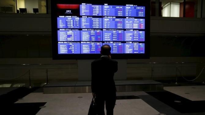 A man looks at an electronic board showing Japan's Nikkei average and related indices at the Tokyo Stock Exchange in Tokyo