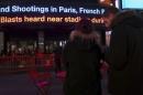 People watch as a news ticker updates people with the news of the shooting attacks in Paris, in Times Square in the Manhattan borough of New York