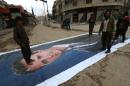 Fighters from a coalition of Islamist forces stand on a huge portrait of Syrian President Bashar al-Assad on March 29, 2015, in the Syrian city of Idlib, the second provincial capital to fall from government control