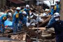 Rescue workers remove debris to search for missing people on August 24, 2014, four days after devastating landslides at a residential area in Hiroshima, western Japan