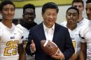 Chinese President Xi Jinping poses with football players and a football he was given during a visit to Lincoln High School, Wednesday, Sept. 23, 2015, in Tacoma, Wash. Xi is on the second of a three-day trip to Seattle before traveling to Washington, D.C., for a White House state dinner on Friday. (AP Photo/Elaine Thompson)