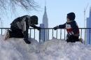 Two boys play atop a pile of snow at the end of a street in Union City