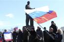 Participants in a pro-Russian rally wave Russian flags in front of a statue of Lenin in Simferopol