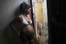 In this Jan. 29, 2016 photo, Tainara Lourenco smiles as she chats with neighbors from the entrance of home at a slum in Recife, Brazil. Unemployed and five months pregnant, 21-year-old Lourenco lives in a slum at the epicenter of Brazil's tandem Zika and microcephaly outbreaks, the state of Pernambuco. (AP Photo/Felipe Dana)