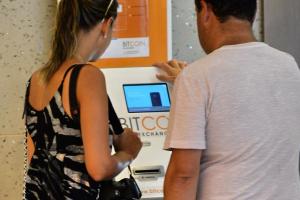 A couple checks a Bitcoin dispensing machine at a shopping …