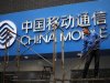 A labourer works in front of a sign for China Mobile at the company's office in downtown Shanghai