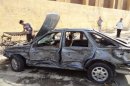 People inspect a destroyed vehicle following a car bomb attack in the northern city of Kirkuk